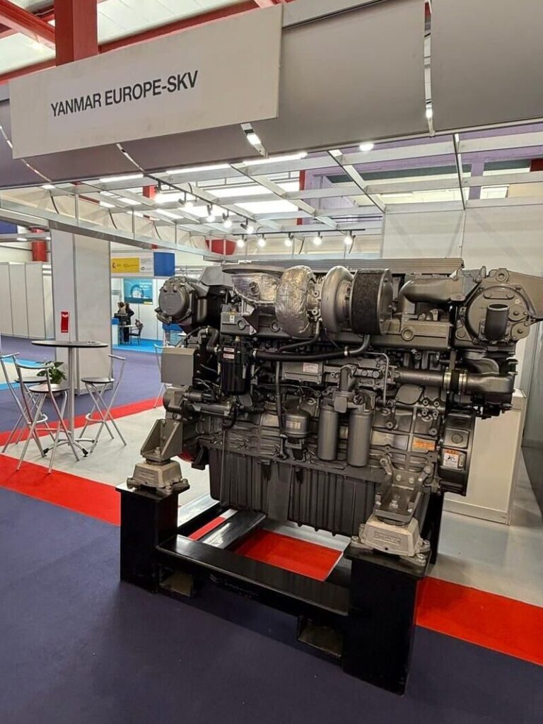 A large industrial engine on display at a trade show. The engine is mounted on a stand.