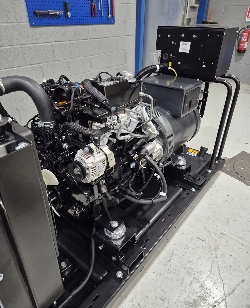 A black industrial engine sits on a metal frame in a workshop. Distribution of spare parts and services for maritime and power plant industries.
